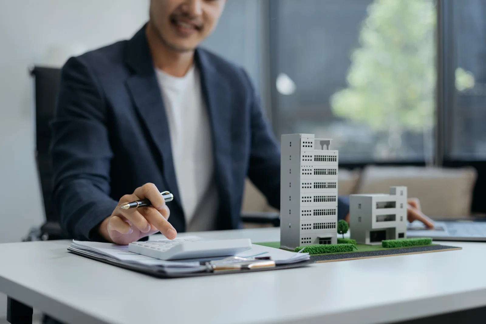 Advisor reviewing property finance figures beside architectural building models